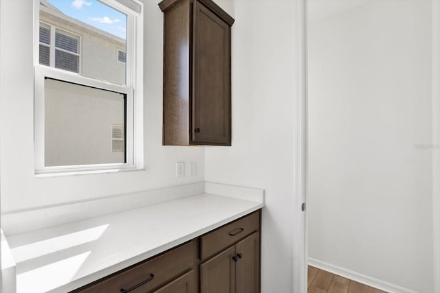 interior space with light countertops, light wood-style flooring, dark brown cabinets, and baseboards