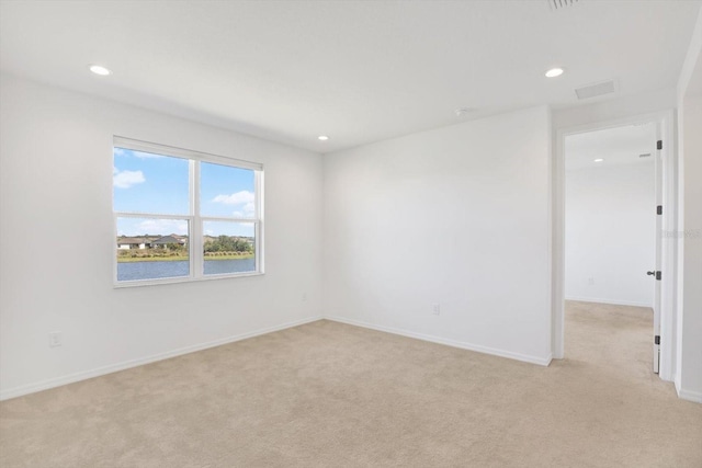 spare room with recessed lighting, light colored carpet, baseboards, and visible vents