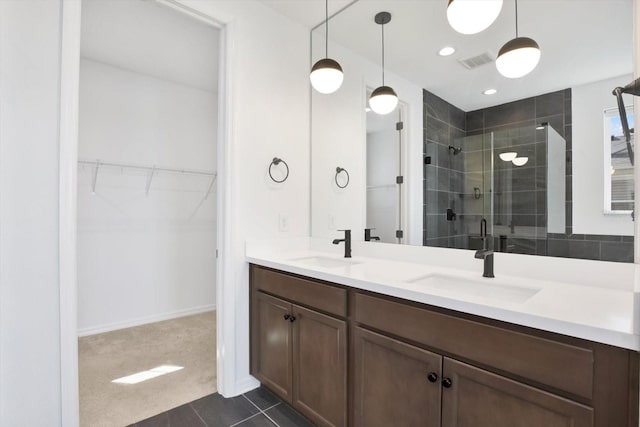 full bath with a spacious closet, visible vents, double vanity, a stall shower, and a sink