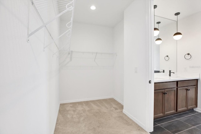 spacious closet with dark colored carpet and a sink