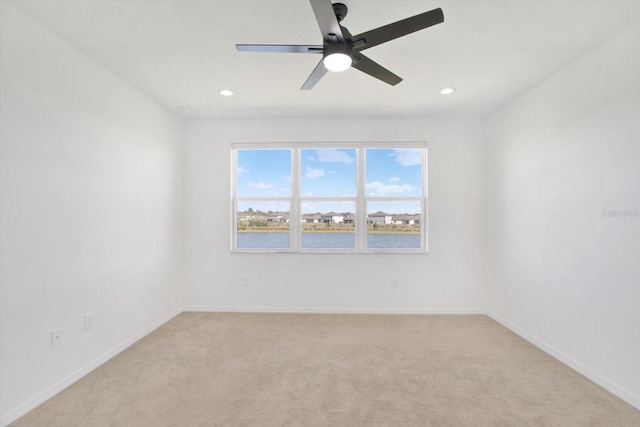 spare room featuring light carpet, recessed lighting, a ceiling fan, and baseboards