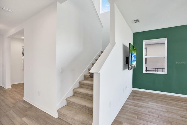 stairway with visible vents, baseboards, and wood finished floors