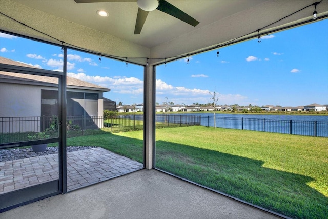 unfurnished sunroom featuring ceiling fan and a water view