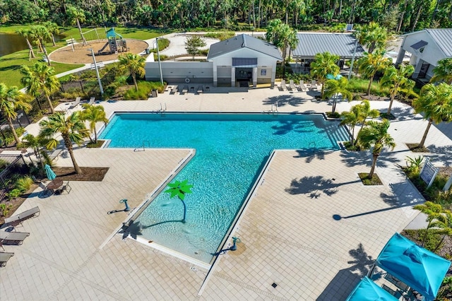 pool with a patio, fence, and playground community