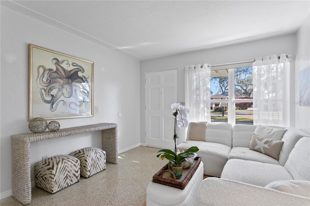 living area with baseboards and speckled floor