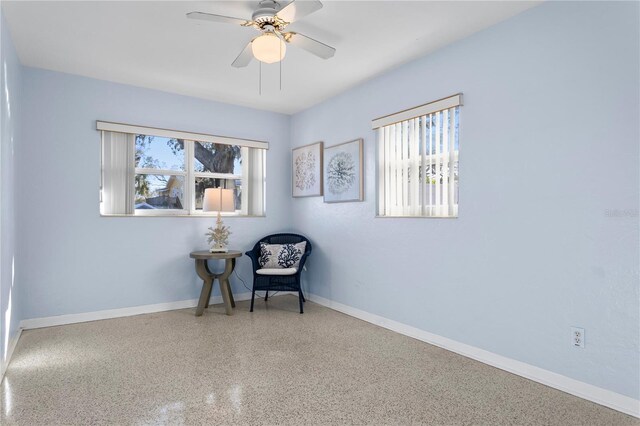 living area with ceiling fan, baseboards, a wealth of natural light, and speckled floor