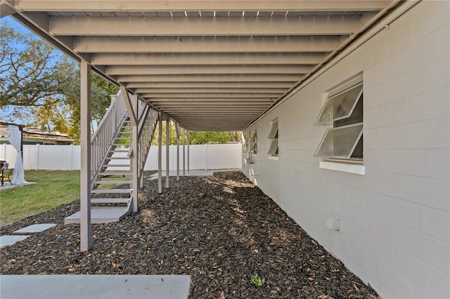 view of yard featuring a carport, fence, and stairs