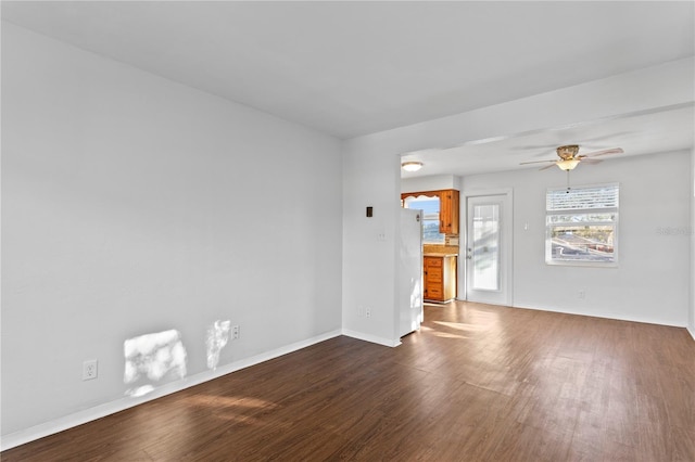 unfurnished room with dark wood-type flooring, ceiling fan, and baseboards