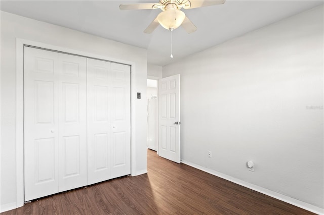 unfurnished bedroom featuring dark wood-type flooring, a closet, ceiling fan, and baseboards