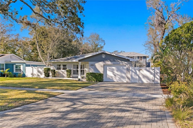 ranch-style house featuring an attached garage, fence, decorative driveway, a gate, and a front lawn