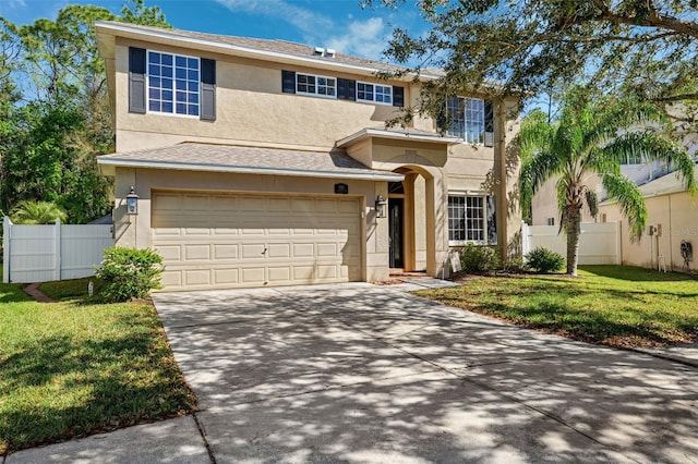 traditional-style house featuring a garage, concrete driveway, fence, and stucco siding