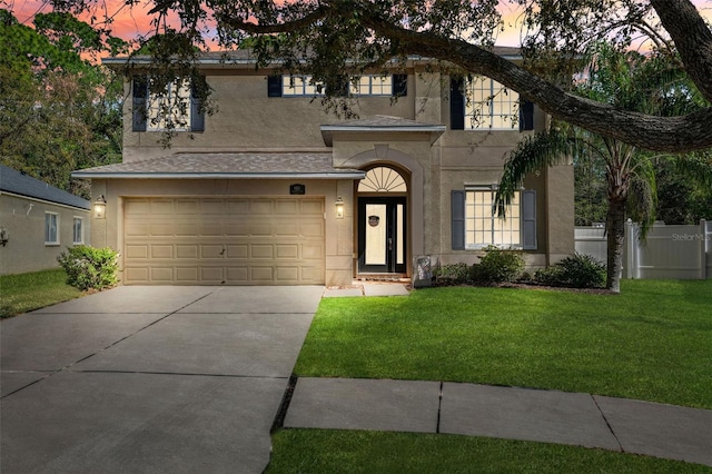 view of front of house featuring driveway, fence, a front lawn, and stucco siding