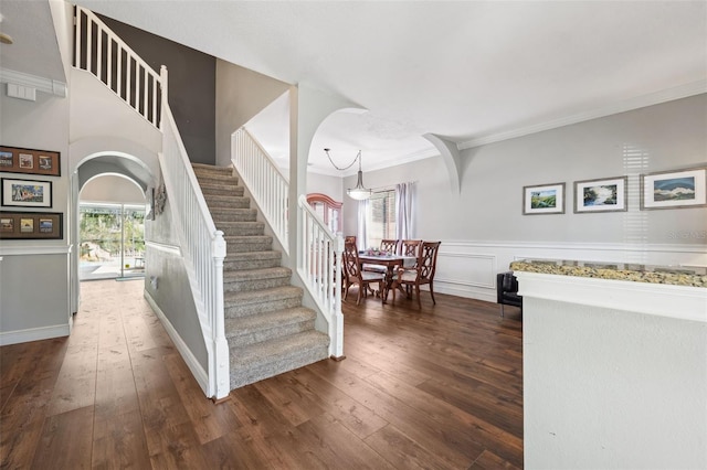 stairway featuring ornamental molding, arched walkways, and wood-type flooring