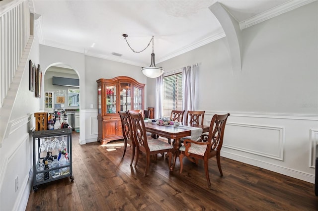 dining area featuring arched walkways, ornamental molding, wainscoting, and dark wood finished floors