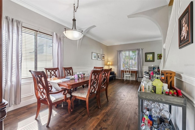 dining room with ornamental molding, arched walkways, a wainscoted wall, and dark wood finished floors