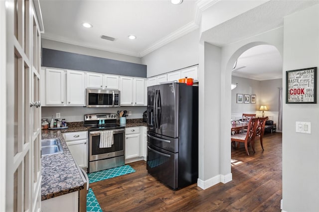 kitchen featuring stainless steel appliances, arched walkways, white cabinetry, and ornamental molding