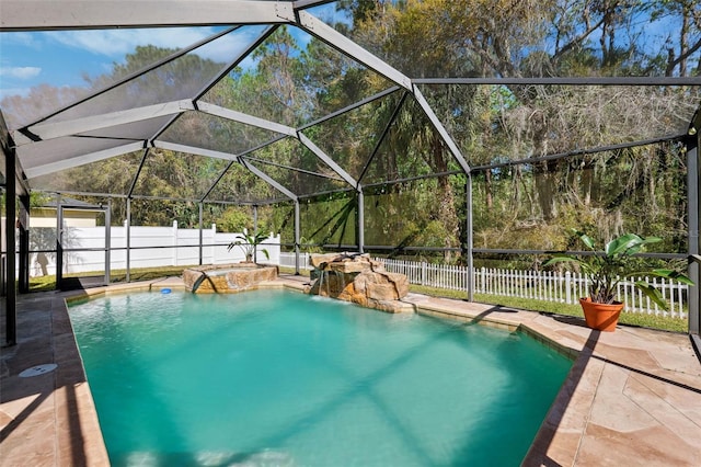 view of pool with glass enclosure, a patio area, a fenced backyard, and a fenced in pool