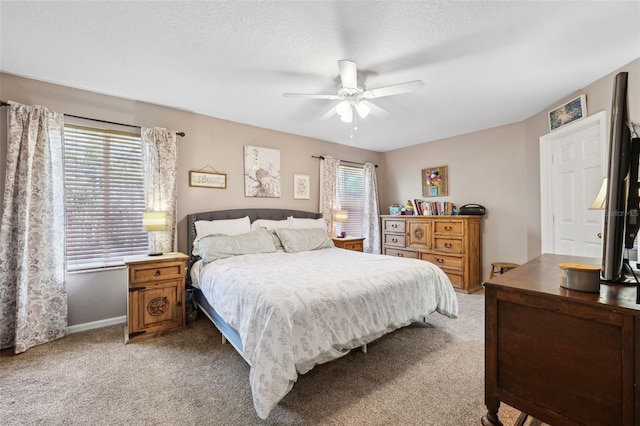 bedroom with light carpet, ceiling fan, a textured ceiling, and baseboards