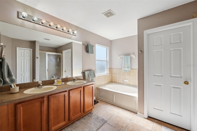 full bath featuring a bath, a stall shower, tile patterned flooring, and a sink