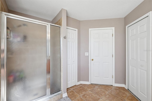 full bathroom featuring a shower stall, baseboards, a closet, and tile patterned floors