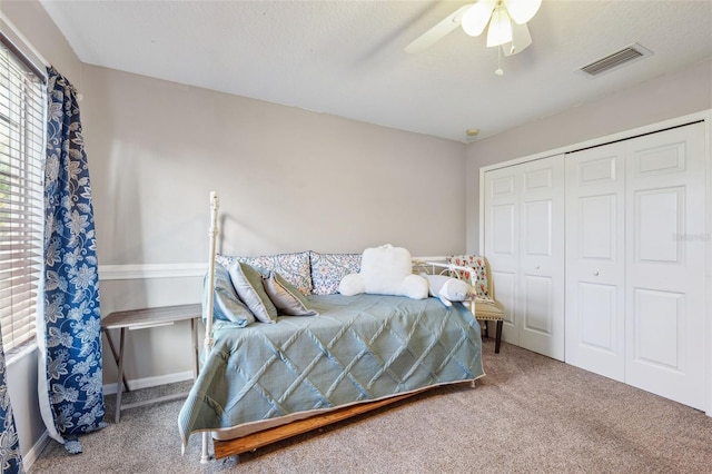 carpeted bedroom with ceiling fan, a closet, visible vents, and baseboards