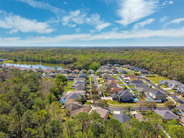 drone / aerial view featuring a forest view, a water view, and a residential view