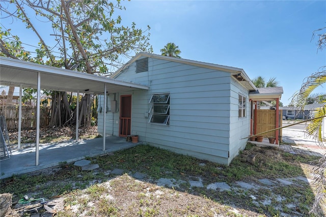 rear view of property with an attached carport and fence