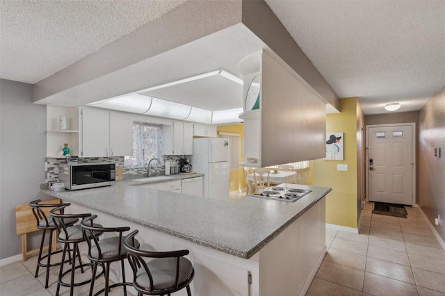 kitchen featuring white appliances, light tile patterned floors, a peninsula, and open shelves