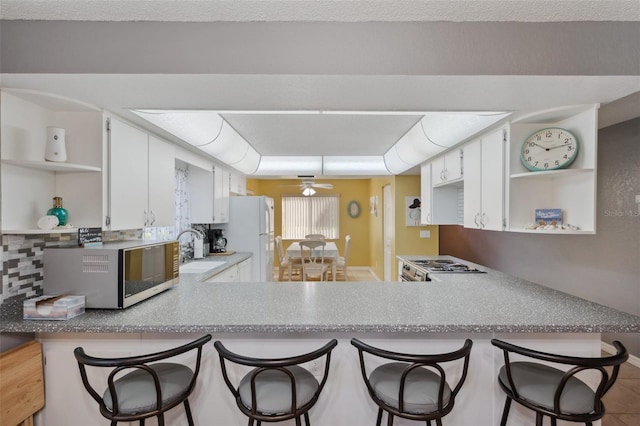 kitchen with a peninsula, stainless steel appliances, open shelves, and a sink