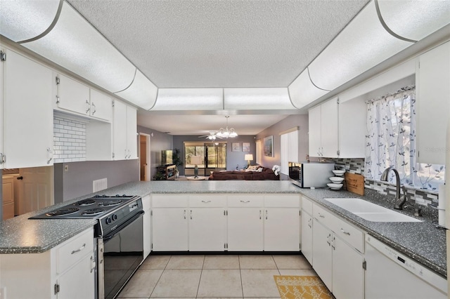 kitchen featuring a tray ceiling, black electric range, stainless steel microwave, a sink, and white dishwasher