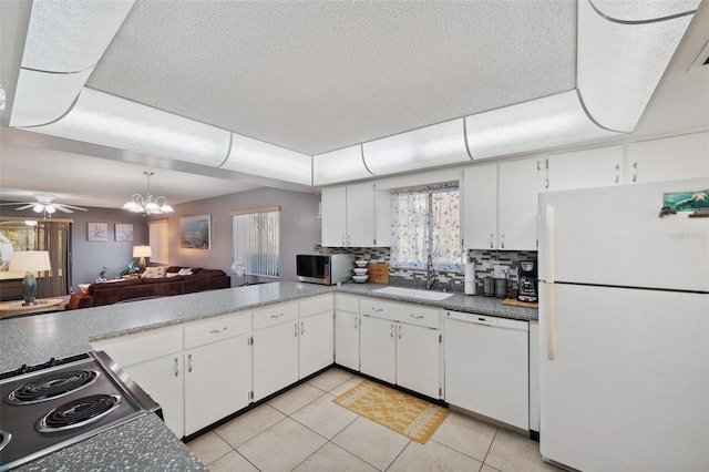 kitchen with backsplash, white cabinets, a sink, white appliances, and ceiling fan with notable chandelier