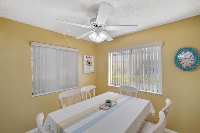 dining space with a textured ceiling, a ceiling fan, and baseboards