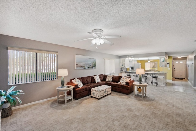 living room with light carpet, ceiling fan with notable chandelier, and baseboards