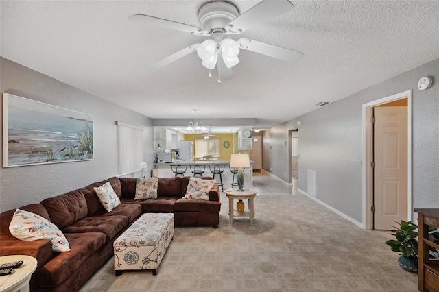 living area with a textured ceiling, a textured wall, light colored carpet, ceiling fan with notable chandelier, and baseboards