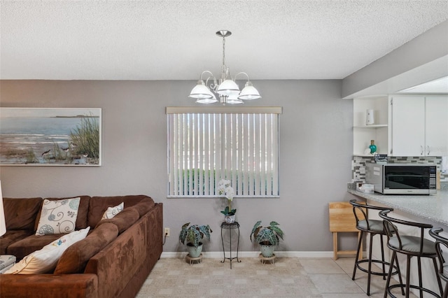 living area featuring light tile patterned floors, a notable chandelier, baseboards, and a textured ceiling