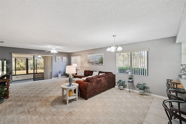 tiled living room featuring visible vents, a textured ceiling, baseboards, and ceiling fan with notable chandelier