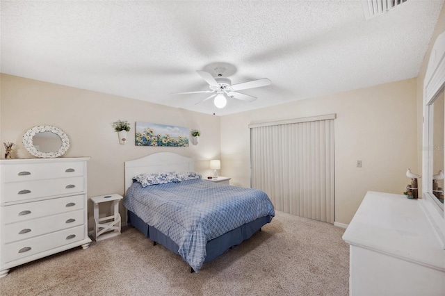 bedroom with light colored carpet, ceiling fan, visible vents, and a textured ceiling