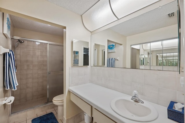 full bathroom featuring a textured ceiling, toilet, a stall shower, and visible vents