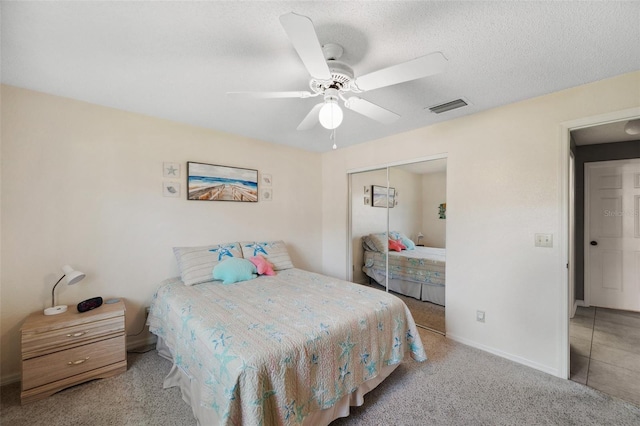 carpeted bedroom with a closet, visible vents, ceiling fan, a textured ceiling, and baseboards