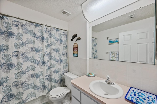 bathroom featuring tile walls, visible vents, toilet, a textured ceiling, and vanity