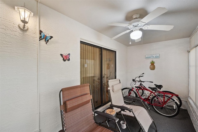 exercise room with a ceiling fan and a textured wall