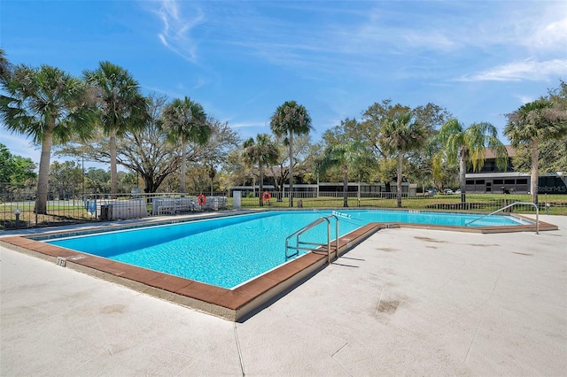 community pool with a patio area and fence