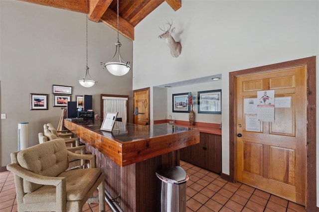 kitchen featuring high vaulted ceiling, light tile patterned flooring, a breakfast bar, hanging light fixtures, and beamed ceiling