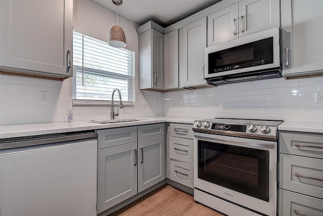 kitchen featuring dishwashing machine, electric range, a sink, light countertops, and gray cabinets