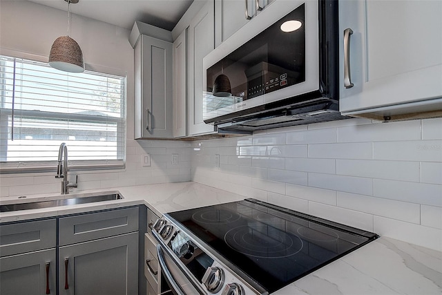 kitchen featuring gray cabinetry, a sink, electric stove, hanging light fixtures, and decorative backsplash