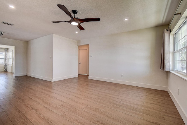 unfurnished room with visible vents, a textured ceiling, and light wood finished floors