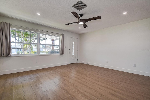 unfurnished room featuring a textured ceiling, wood finished floors, visible vents, and a healthy amount of sunlight