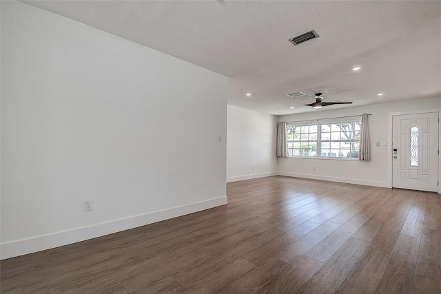 interior space featuring a ceiling fan, baseboards, visible vents, and dark wood-style flooring