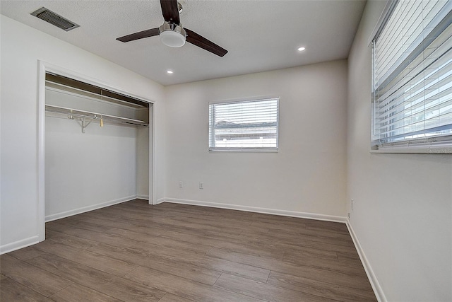 unfurnished bedroom with a closet, visible vents, baseboards, and wood finished floors