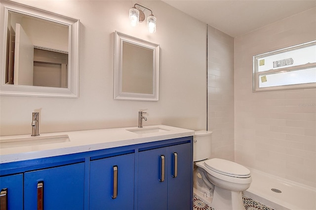 full bath featuring a sink, a tile shower, toilet, and double vanity